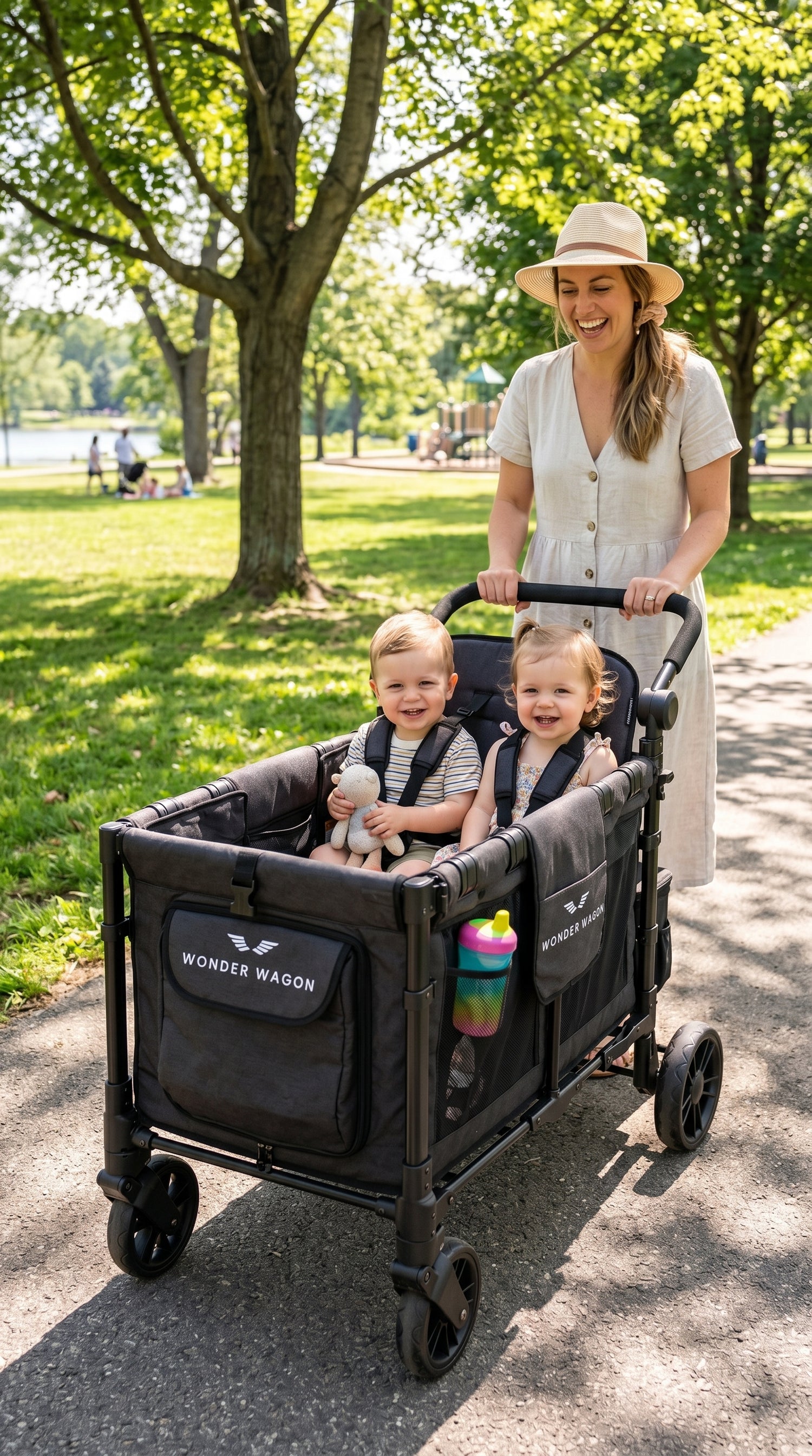 Mom pushing two toddler twins in a Wonder Wagon stroller wagon at a sunny South African park